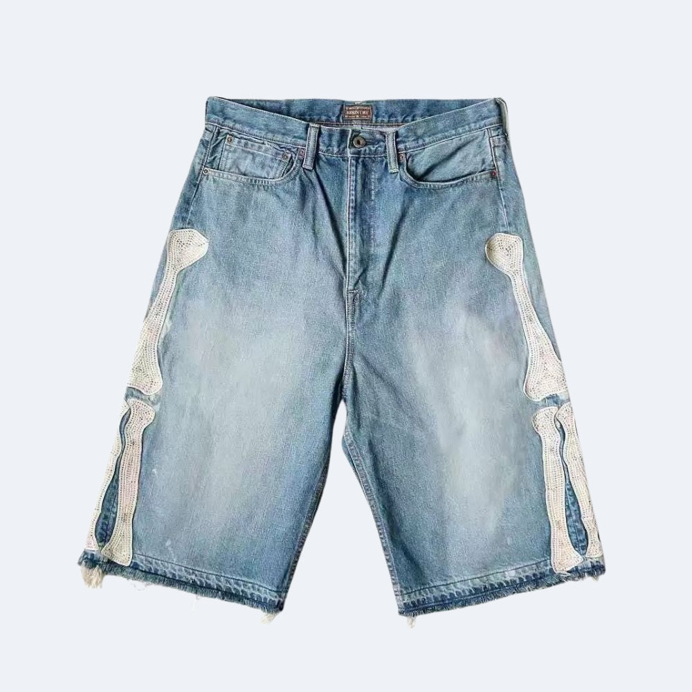 Light blue denim shorts with decorative bone appliques on the outer thighs and frayed hems, shown flat against a light gray background.