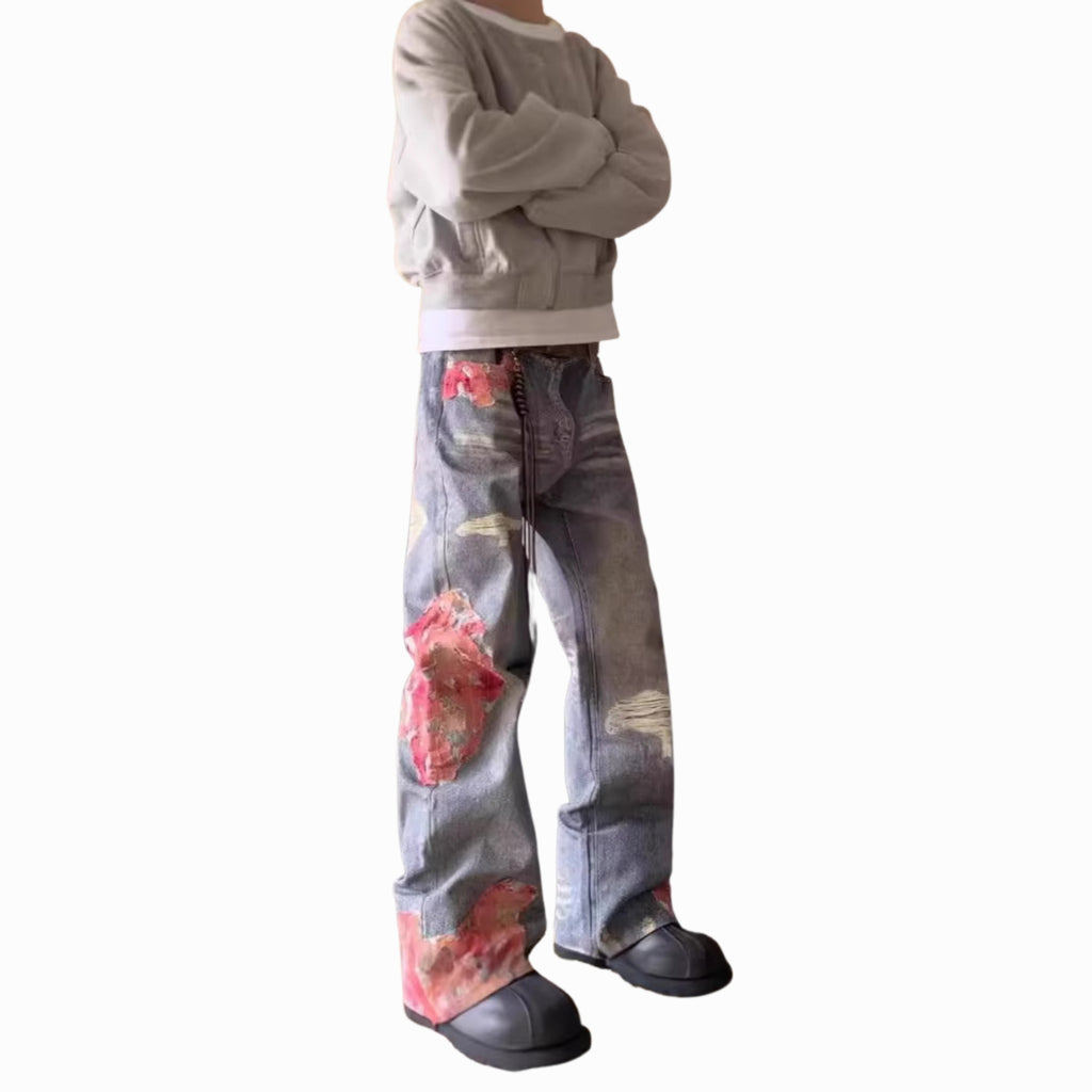 Person wearing a gray sweatshirt and floral jeans on a white background