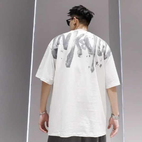 Person wearing a white t-shirt with black text on the back against a gray background