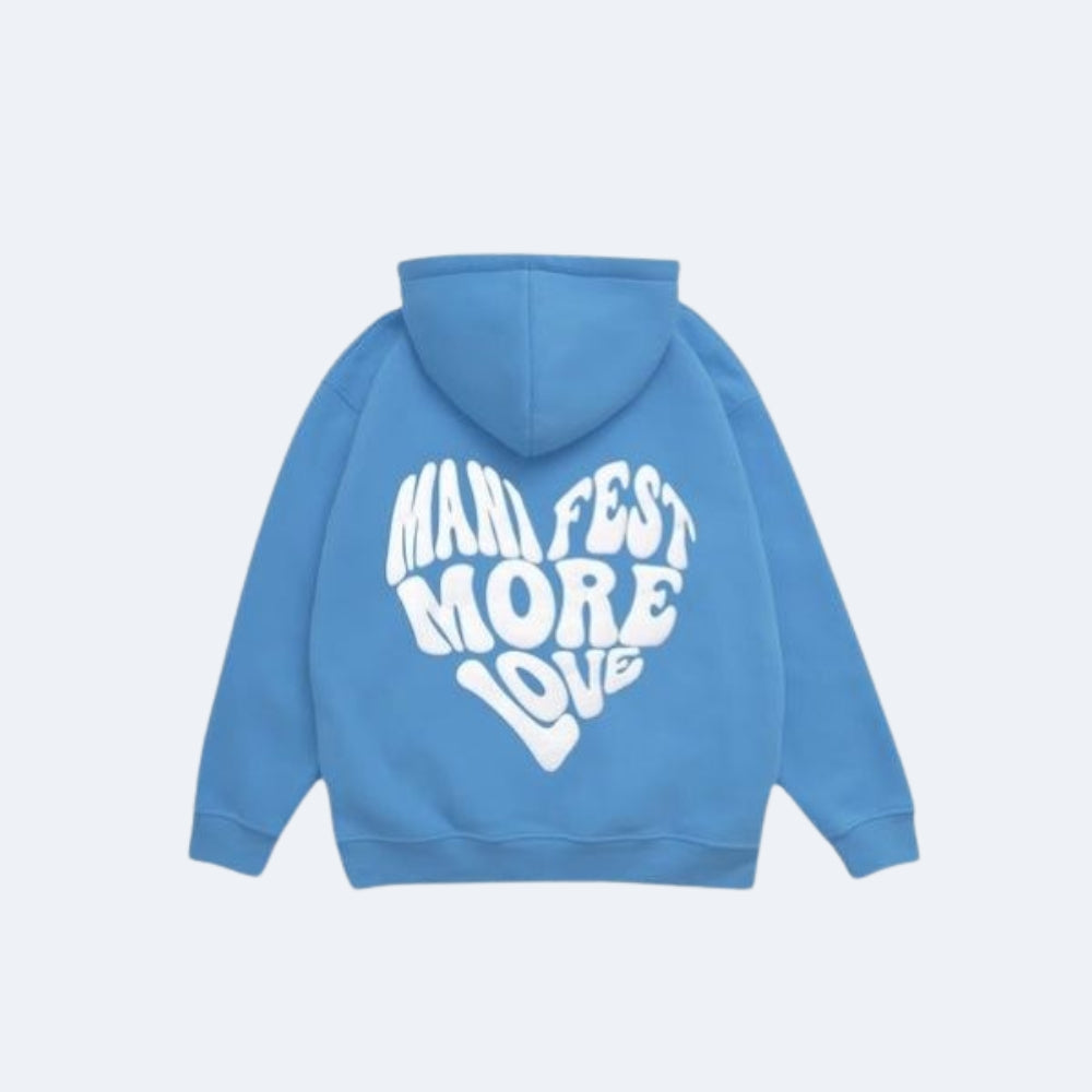 Blue. A light blue hoodie shown from the back, featuring a large white graphic text that reads MANIFEST MORE LOVE in a retro, wavy font.