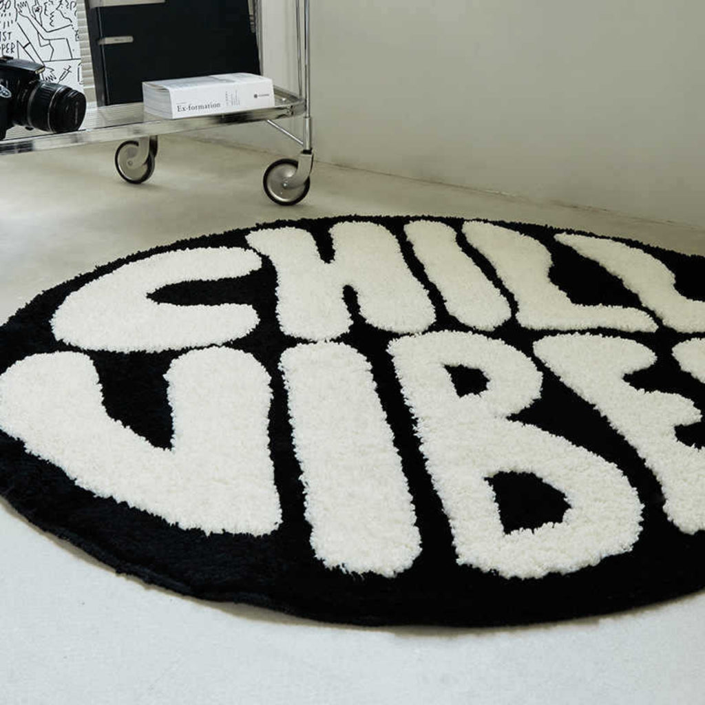 Round black rug with white text 'CHILL VIBES' on a light-colored floor.