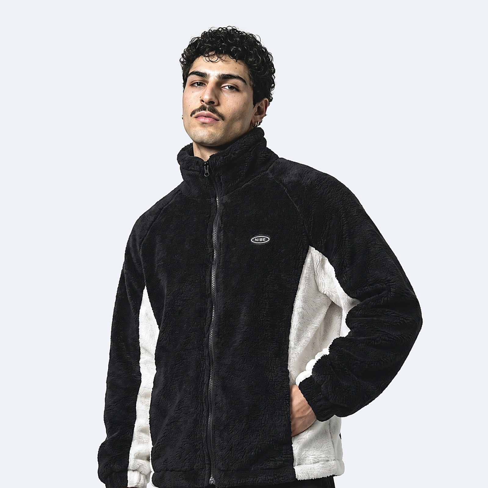 Black. A man wearing a black and off-white fleece zip-up jacket with a small oval logo on the left chest.