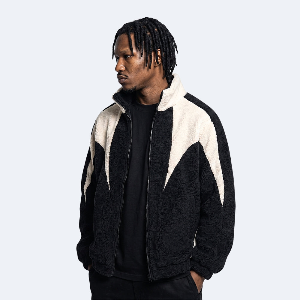 Black. A man wearing a black and cream sherpa fleece zip-up jacket, styled over a black t-shirt.