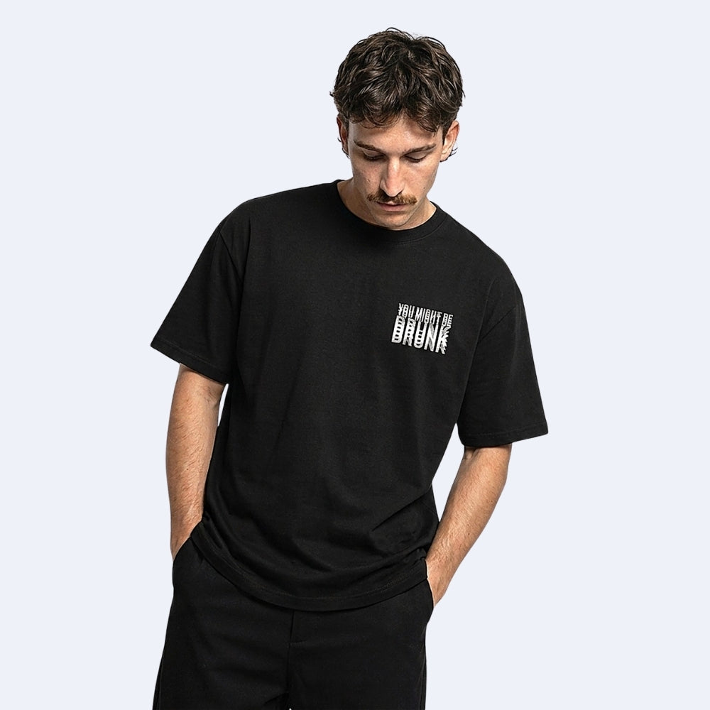 Black. KRUX You Might Be Drunk black oversized tee, front view on a male model with small chest print