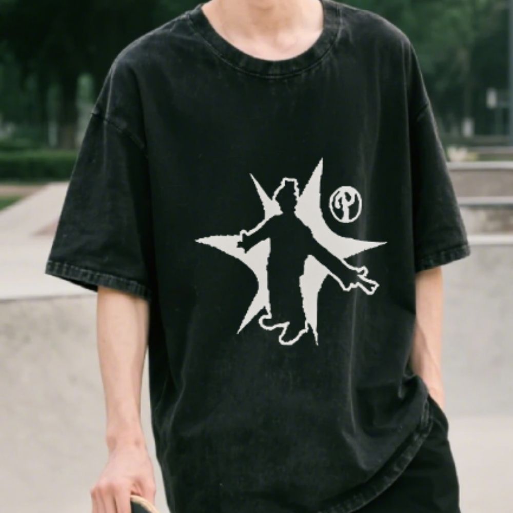 Person wearing a black t-shirt with a white graphic design outdoors.