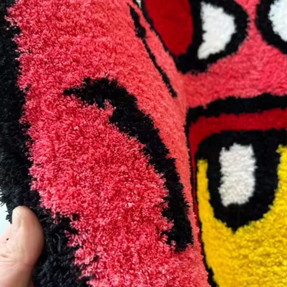Close-up of a colorful plush toy with a cartoon face, held by a hand.