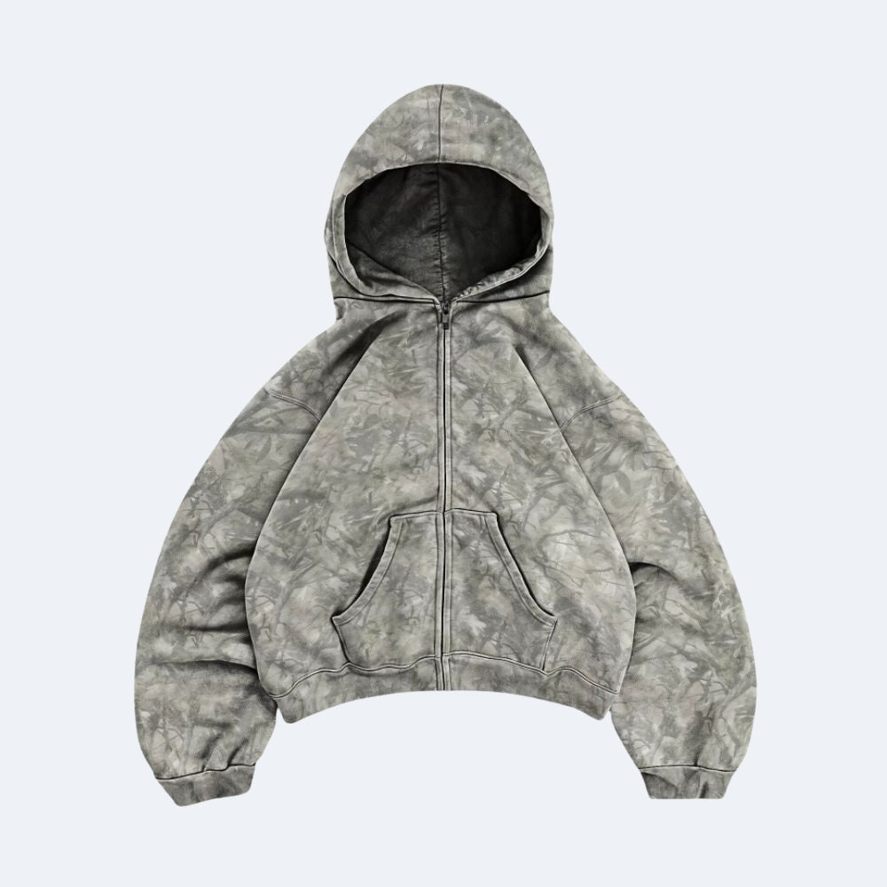 Gray. A cropped zip-up hoodie with a gray and white mineral-wash tie-dye pattern, featuring a black-lined hood and front pockets.