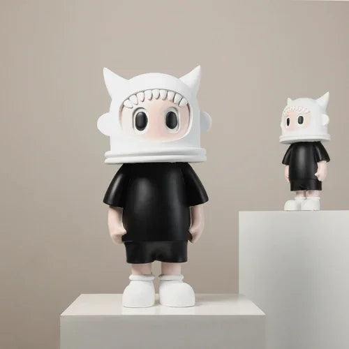 Two small figurines with white hats and black outfits on a neutral background
