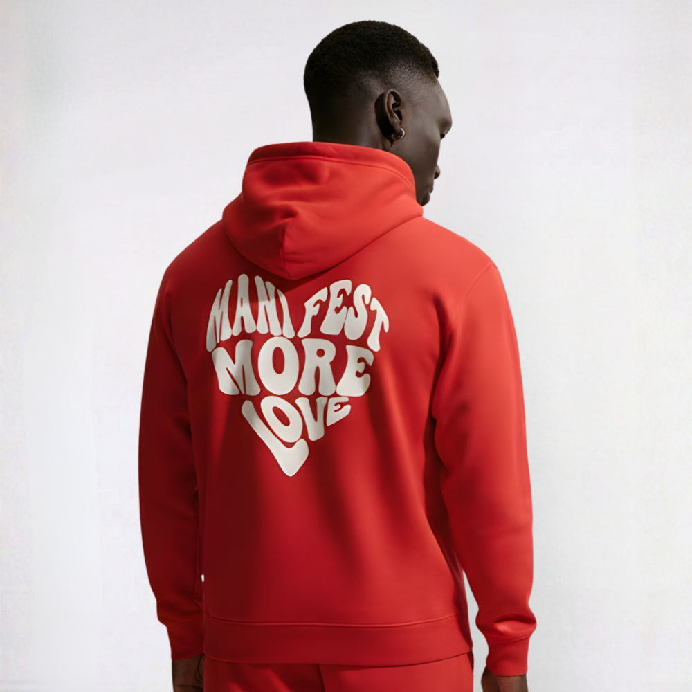 Person wearing a red hoodie with 'Manifest More Love' text on the back against a white background