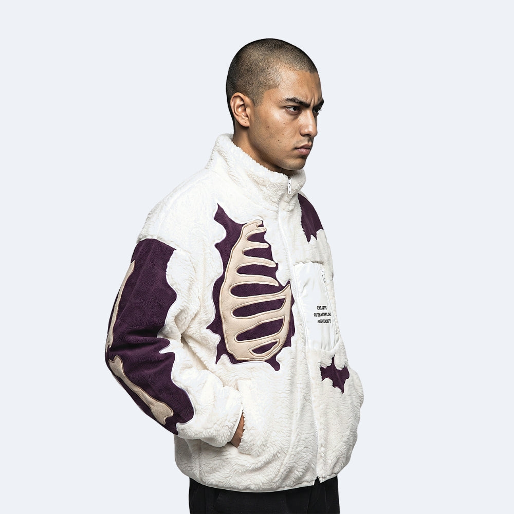 White. A man wearing a white sherpa fleece jacket with dark purple and beige rib cage graphics.