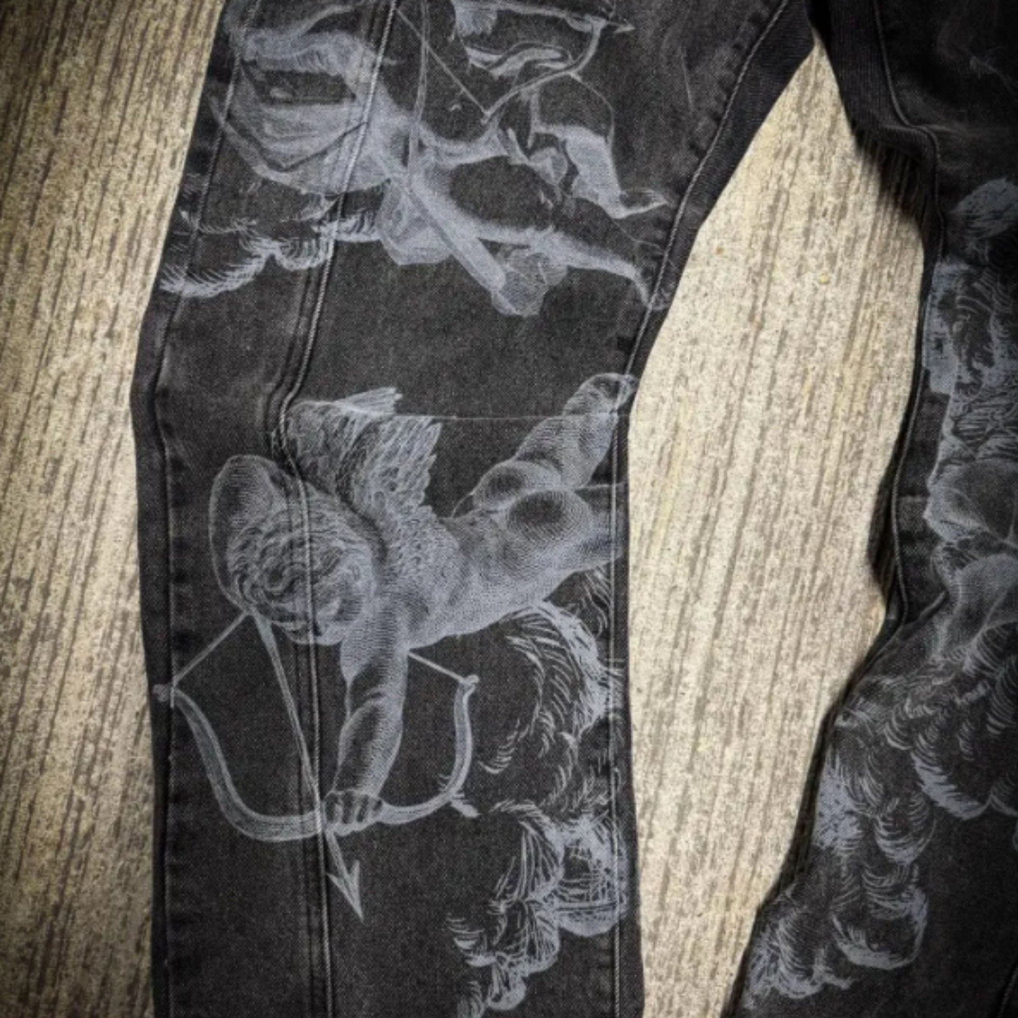 Black pants with white floral and archery design on a wooden surface