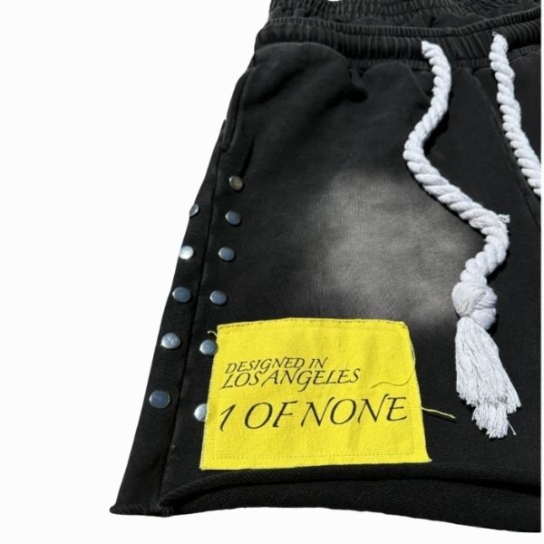 Black garment with a yellow label reading 'Designed in Los Angeles 1 of None' on a white background