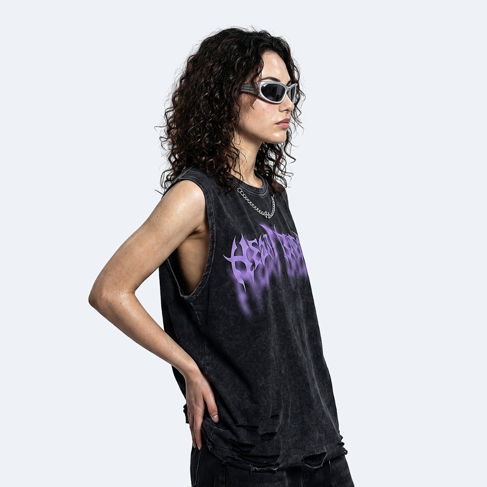 A model with curly dark hair and cat-eye sunglasses wearing a washed black sleeveless tank top with a purple graphic print, posed against a light gray background.