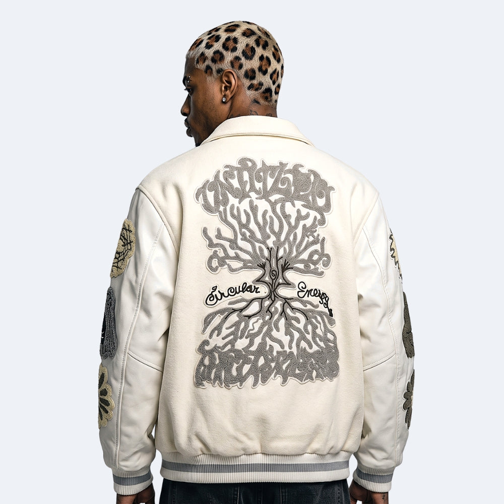 White. A man viewed from behind wearing a cream-colored jacket with a large gray tree graphic and gothic text across the back, with gray ribbed trim at the collar, cuffs, and hem.