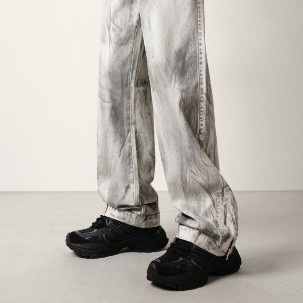 Person wearing light gray pants and black shoes on a plain background