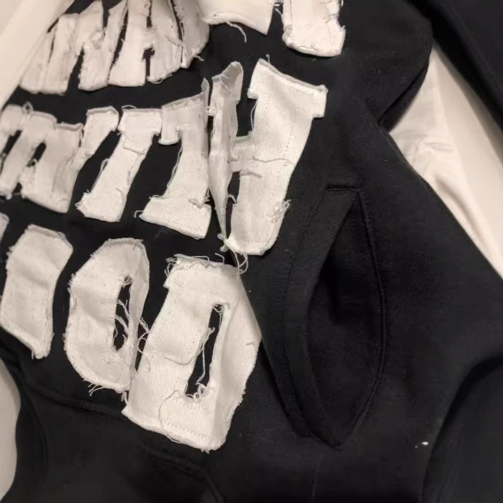 Black hoodie with white text and fabric pieces on a white background