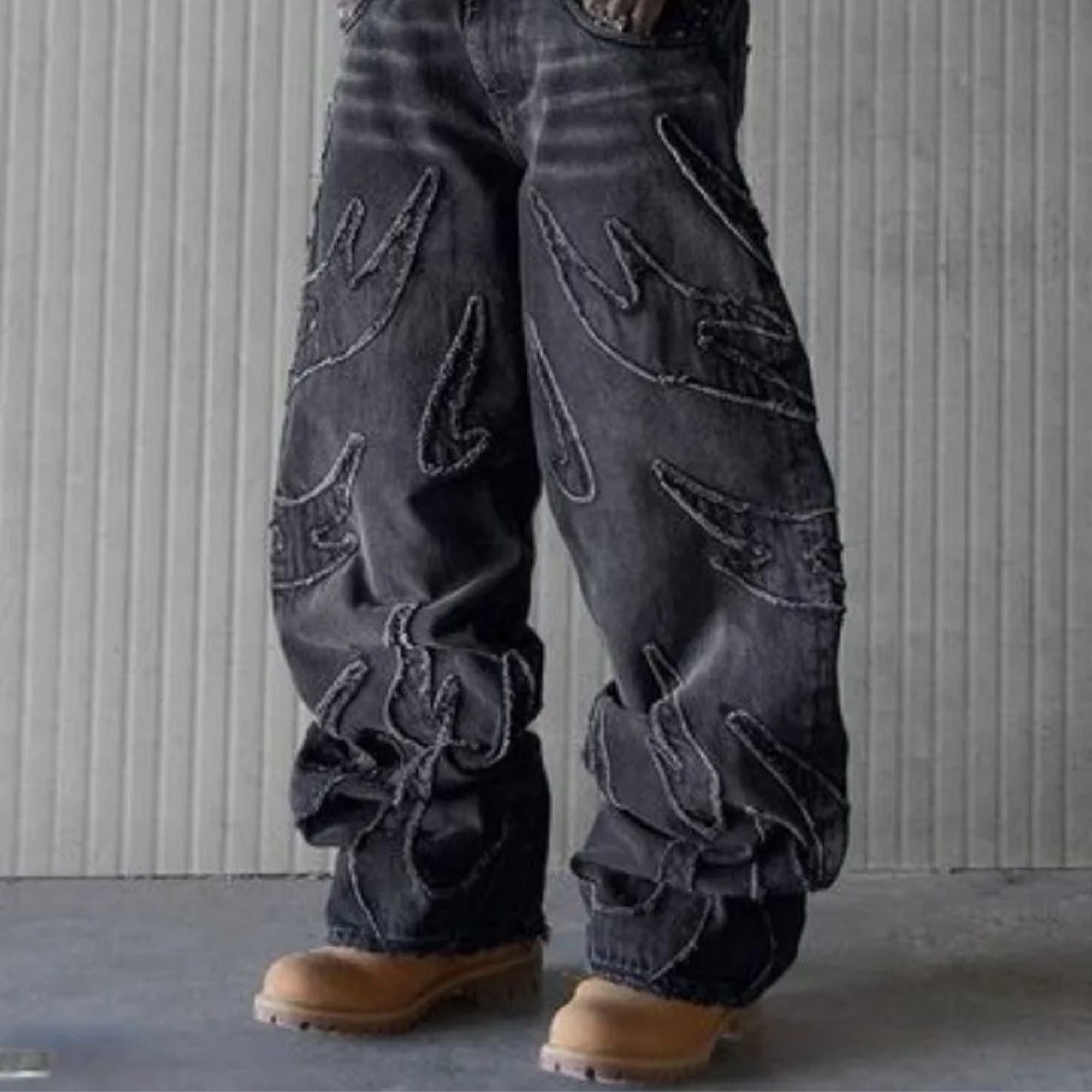 Dark blue jeans with embroidered designs worn by a person against a neutral background
