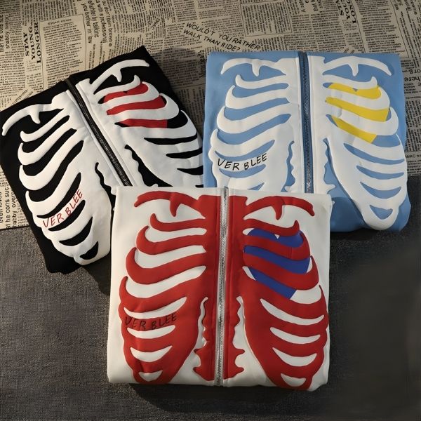Four zip-up hoodies with skeleton designs on a textured surface.