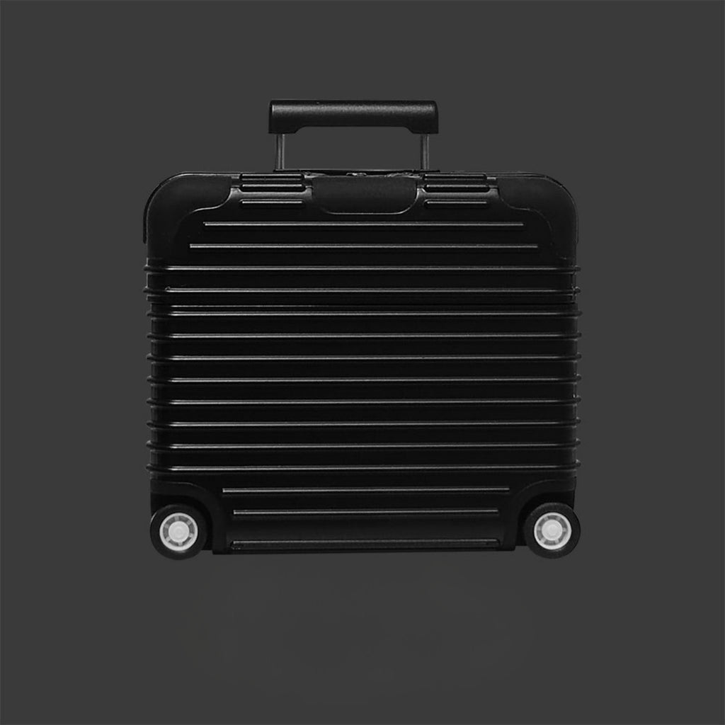 Black suitcase AirPods case with a ribbed texture on a dark gray background