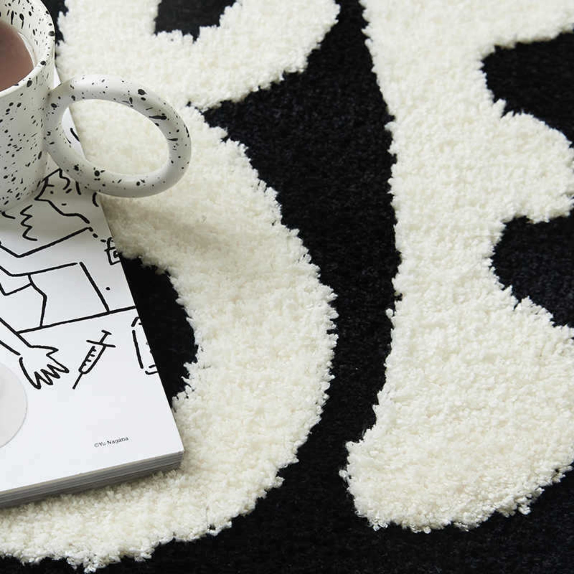 White textured rug with a cup and book on a black surface