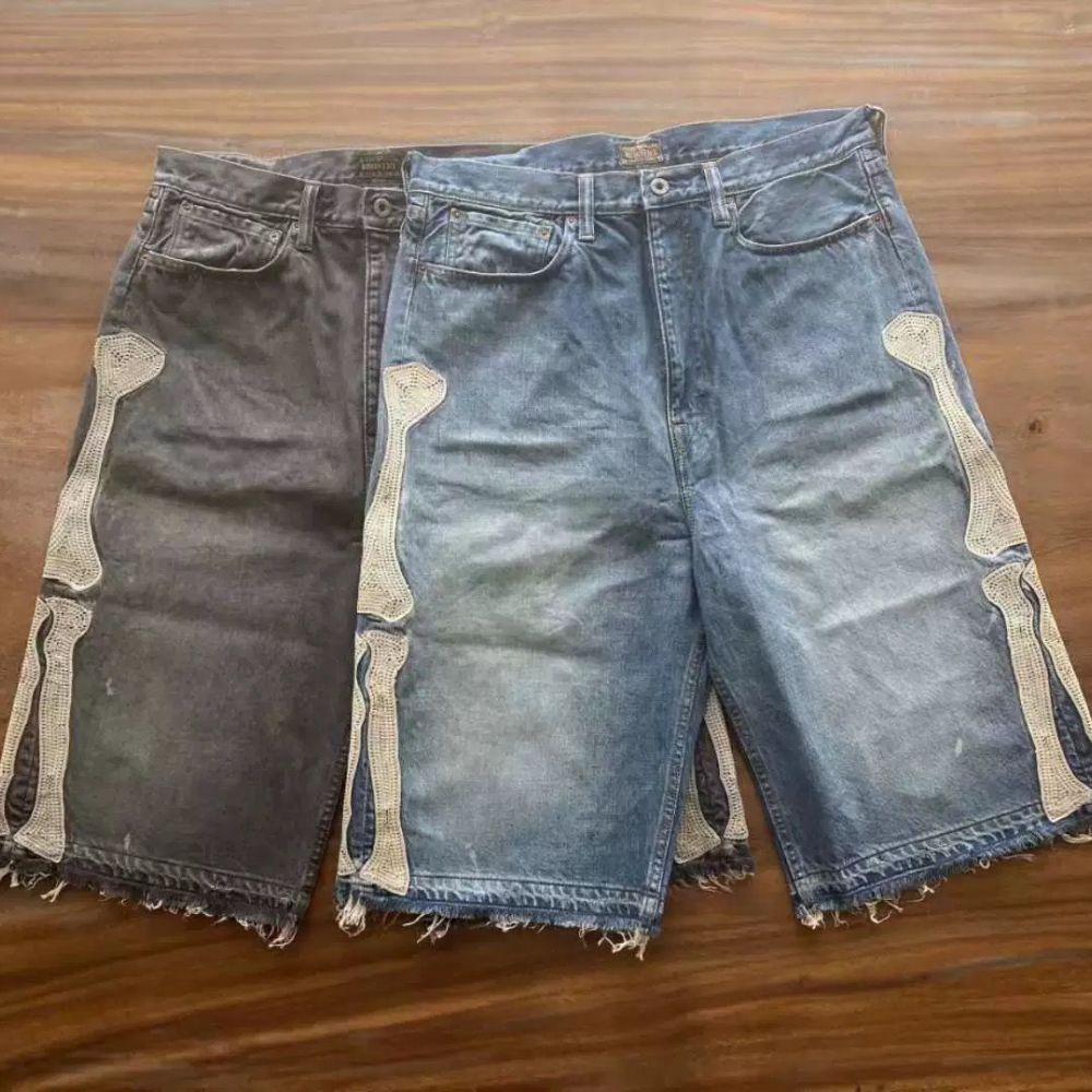 Two pairs of denim shorts with skeleton designs on a wooden surface