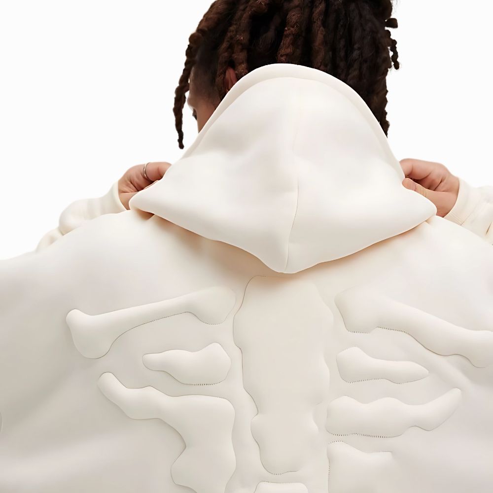 Person wearing a white hoodie with abstract patterns on a plain background