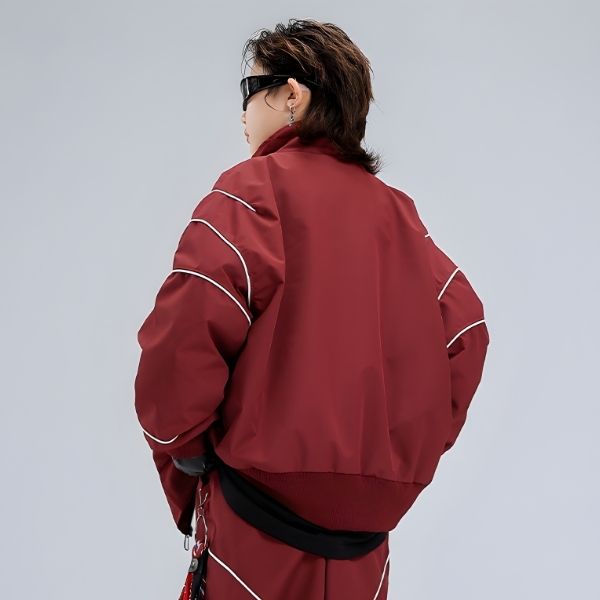 Person wearing a red jacket with white piping on a gray background