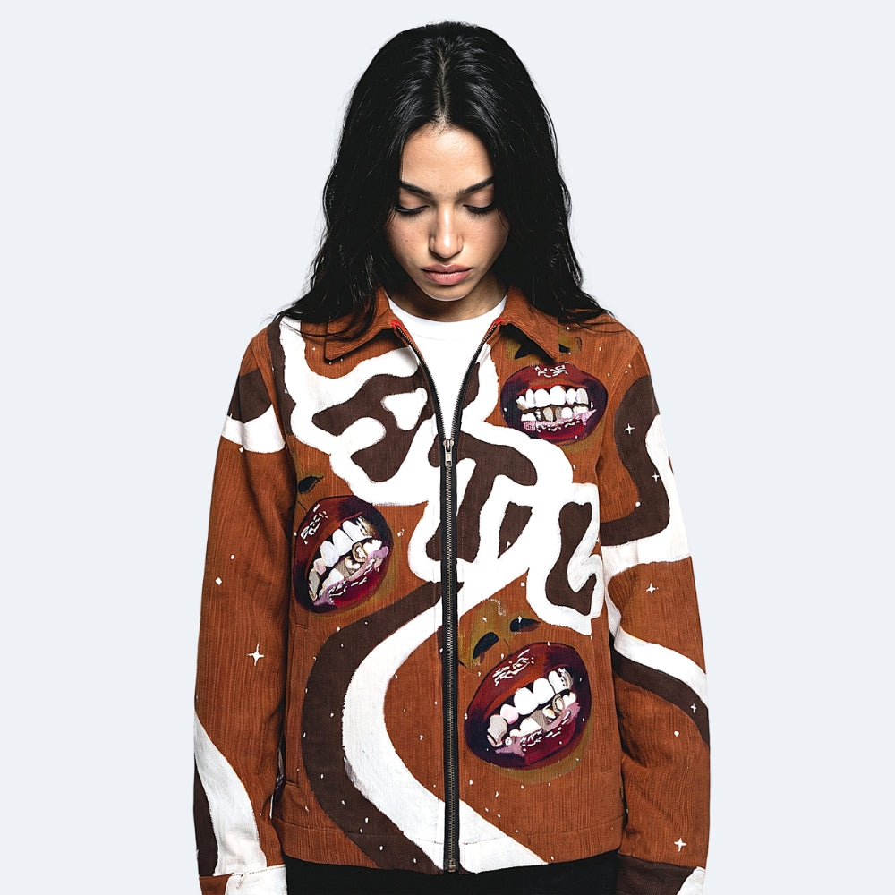 A model wearing a brown corduroy jacket with a white graphic print and three graphic mouth patches showing teeth, set against a light gray background.