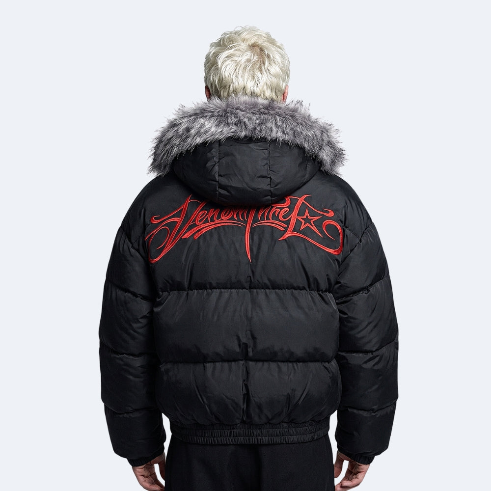 A person shown from the back wearing a black puffer jacket with a gray faux-fur hood trim and a large red script logo across the upper back, photographed against a light gray studio background.