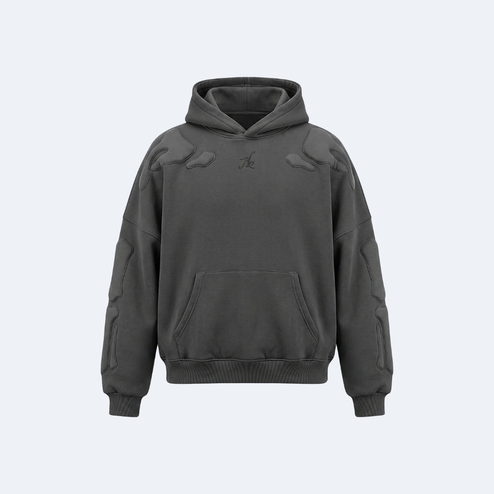 Black. A dark gray oversized hoodie with quilted panel details on the shoulders and sleeves, a tonal embroidered logo on the chest, and a front kangaroo pocket.