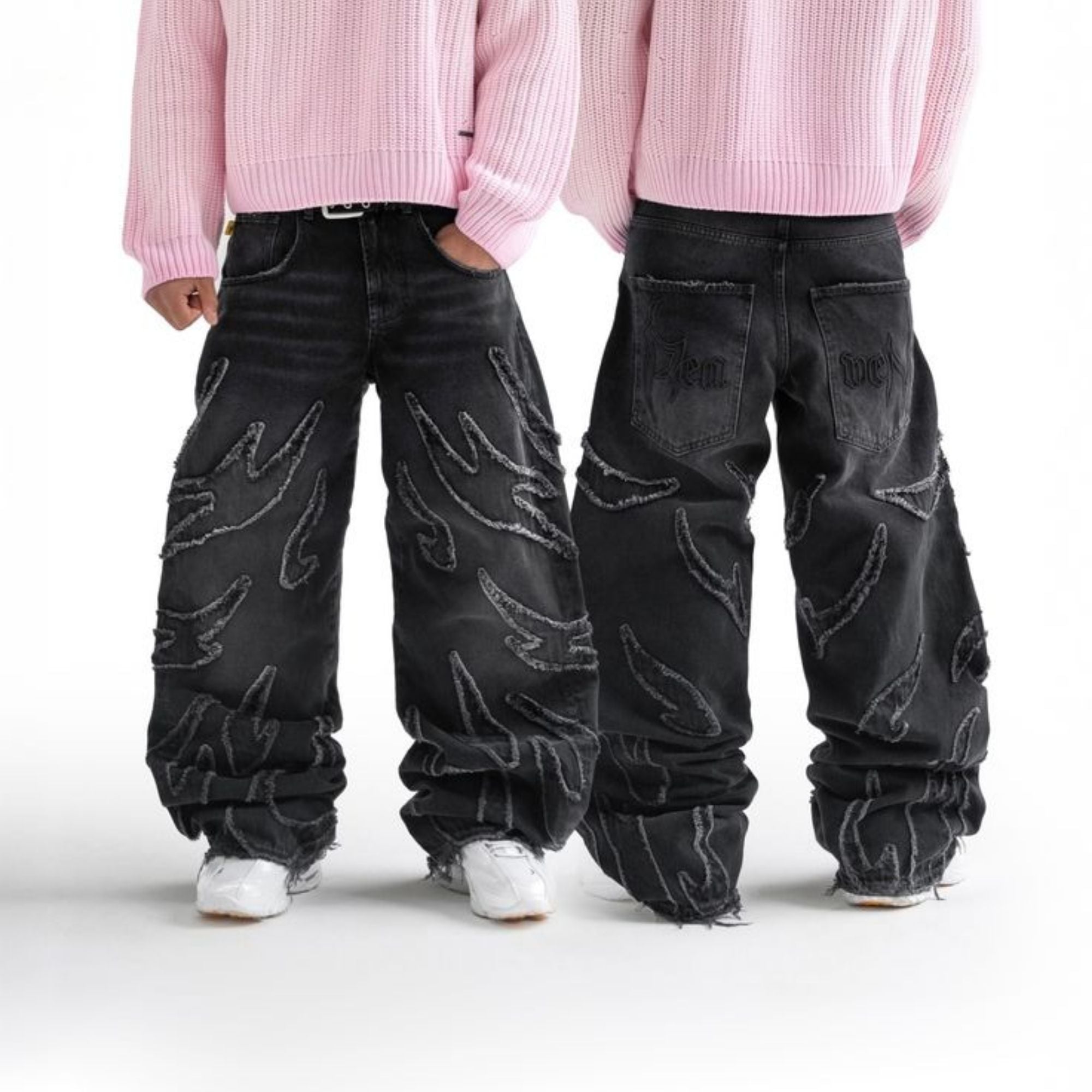 Two people wearing black jeans with white patterns on a white background
