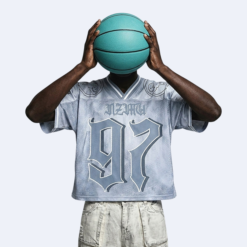 A person wearing a light blue mesh basketball jersey with 'JAZZACH' and the number '97' on the front, holding a teal basketball in front of their head against a light gray background.