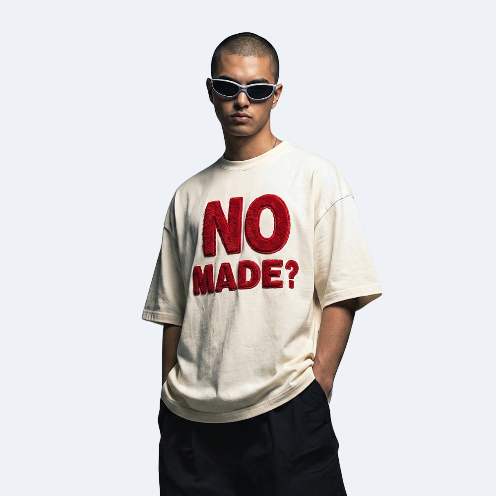 Beige. A model wearing the KRUX No Made tee in beige with textured lettering.