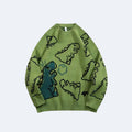 Green. A light olive green crewneck sweater featuring a playful cartoon dinosaur pattern with black outlines and a teal-green dinosaur graphic on the front.