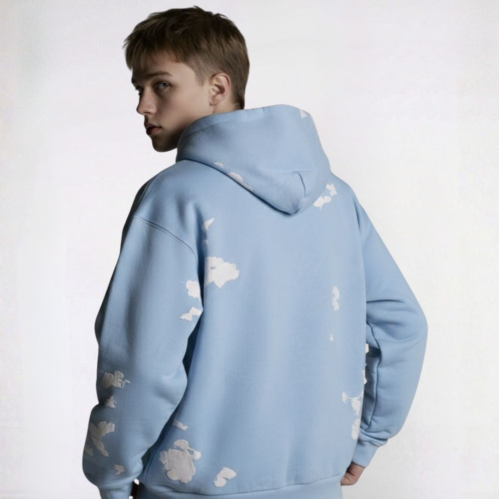 Person wearing a light blue hoodie with cloud patterns on a white background