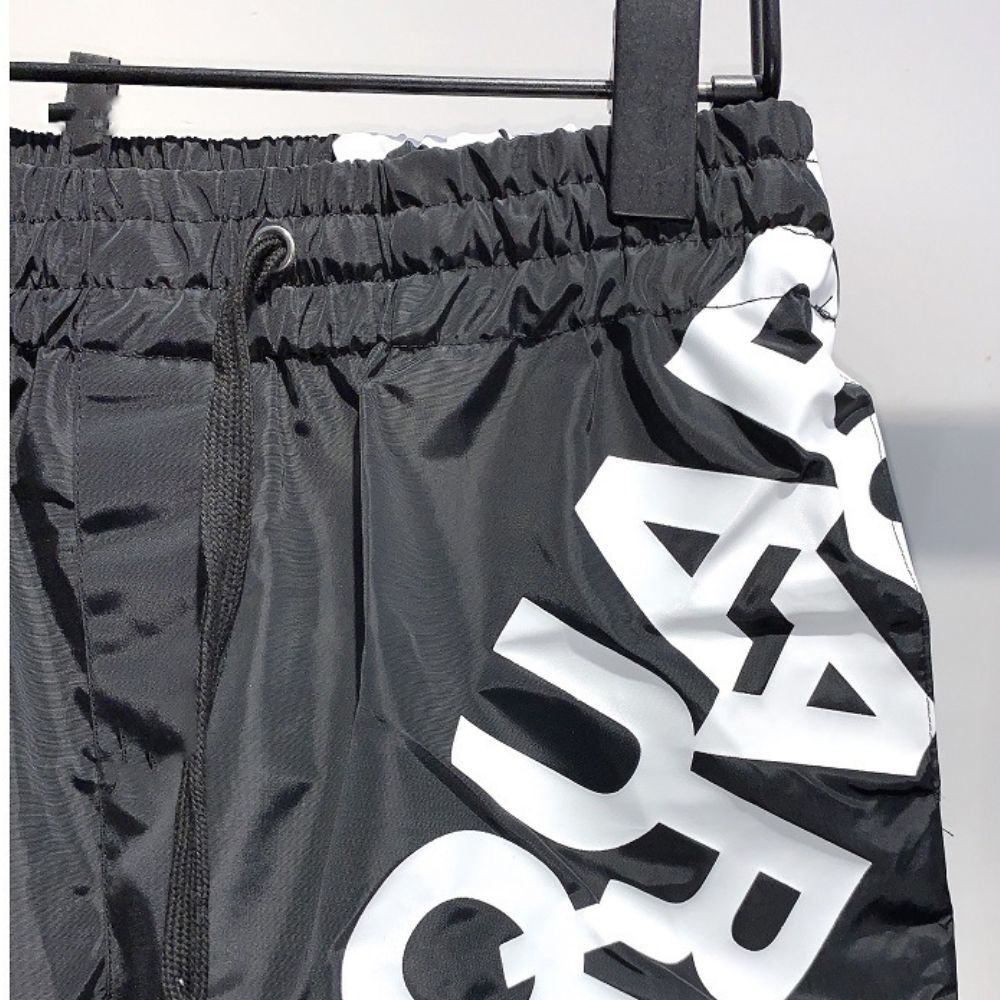 Black shorts with white branding on a hanger against a light background