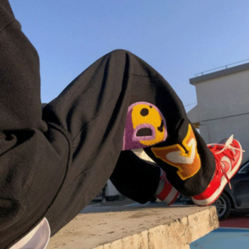 Person wearing colorful socks with a cartoon design and red sneakers, standing on a ledge.