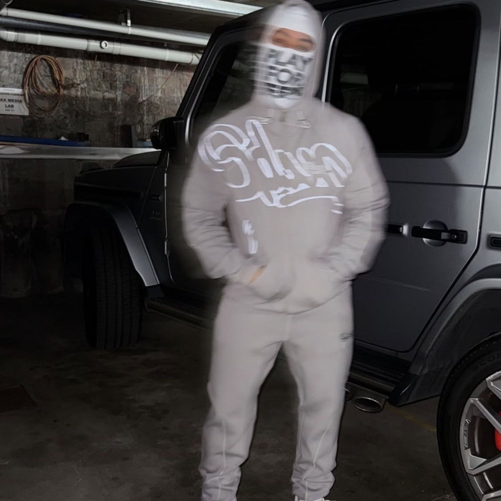 Person wearing a gray hoodie and pants with text in a garage