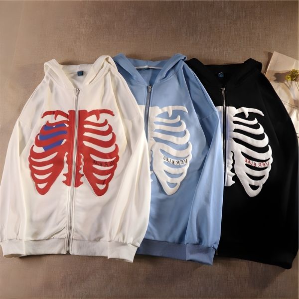 Three hoodies with ribcage designs on a brown surface