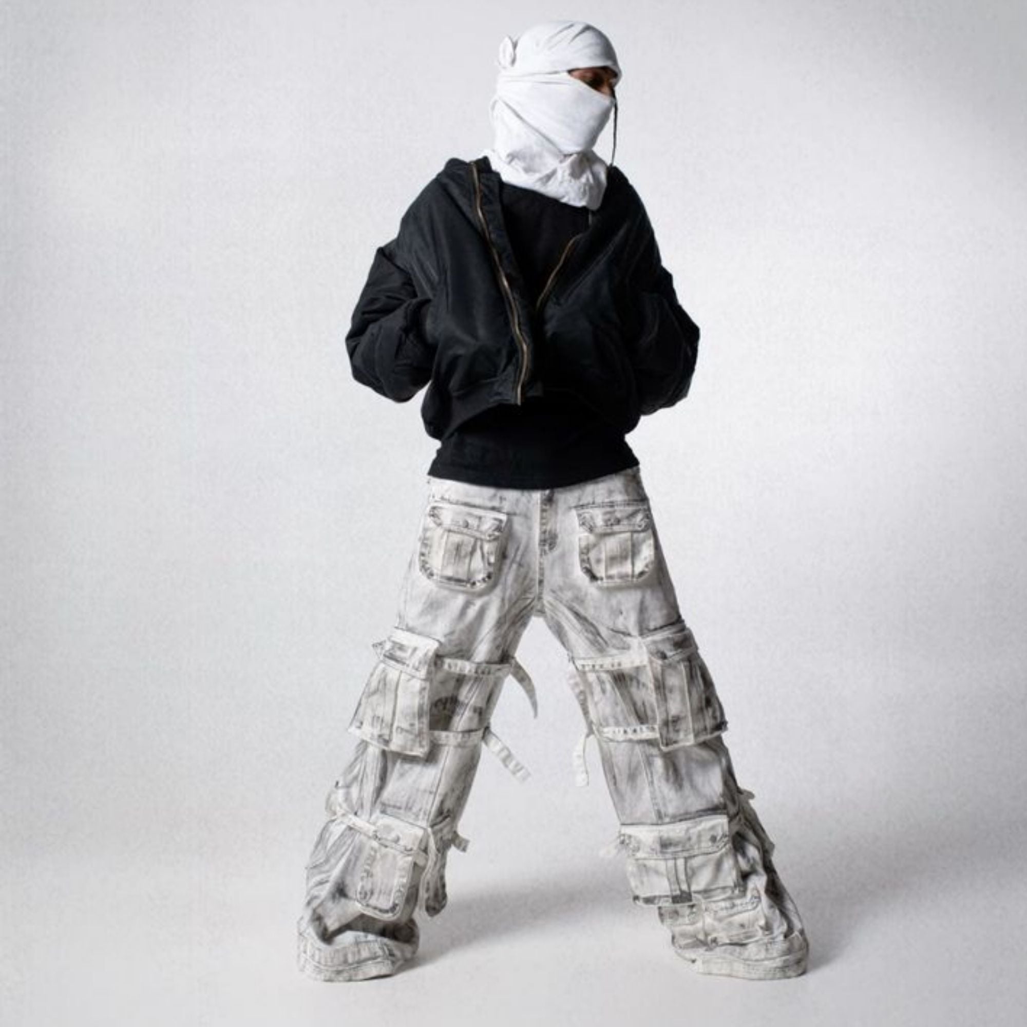 Person wearing a black jacket and light gray cargo pants on a white background