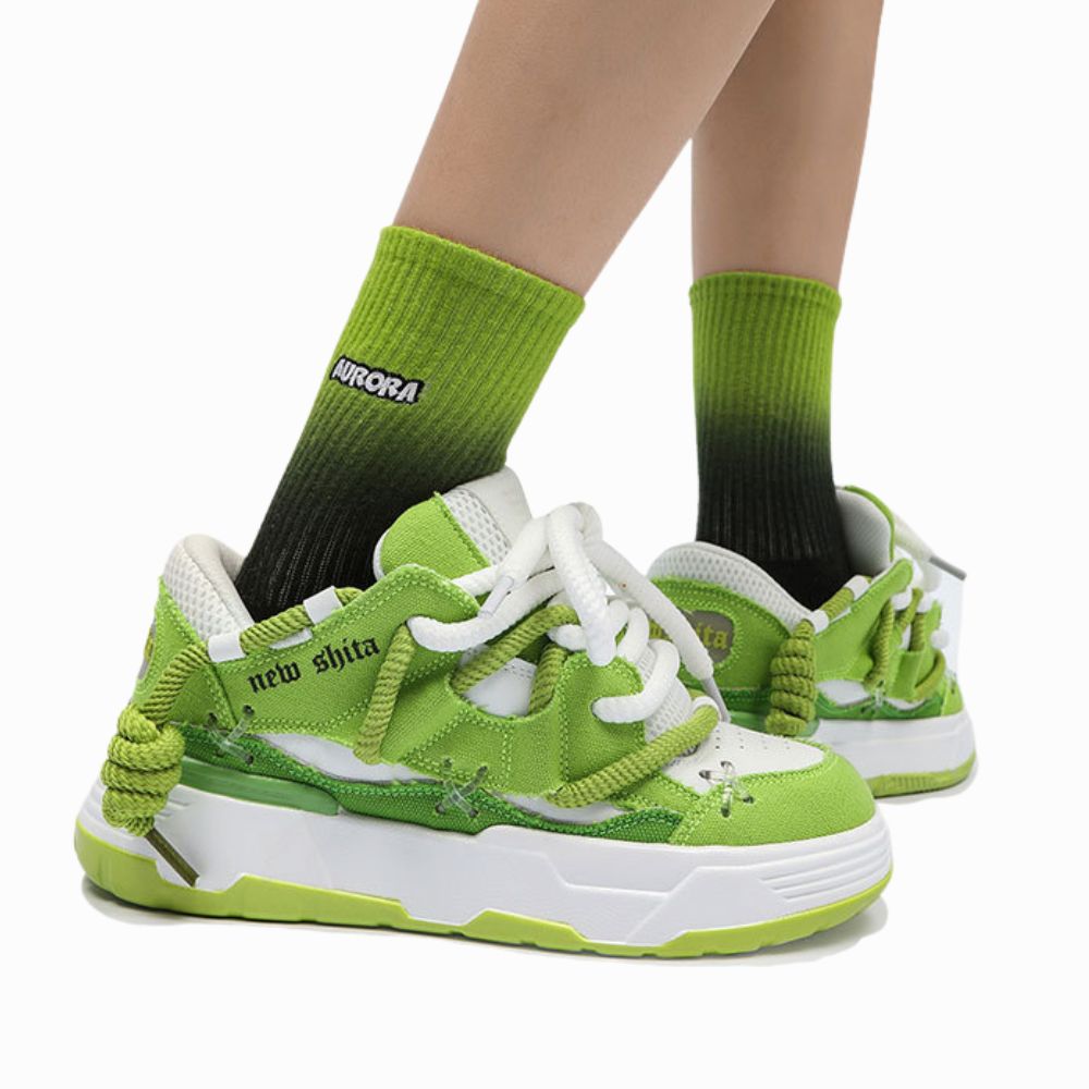 Green sneakers with white soles worn with green socks on a white background