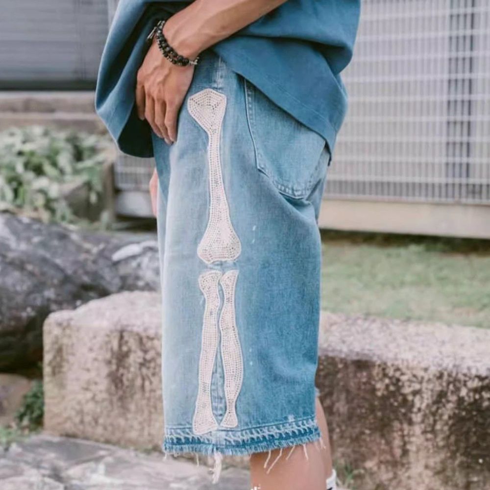 Person wearing a blue denim skirt with a skeleton design outdoors.