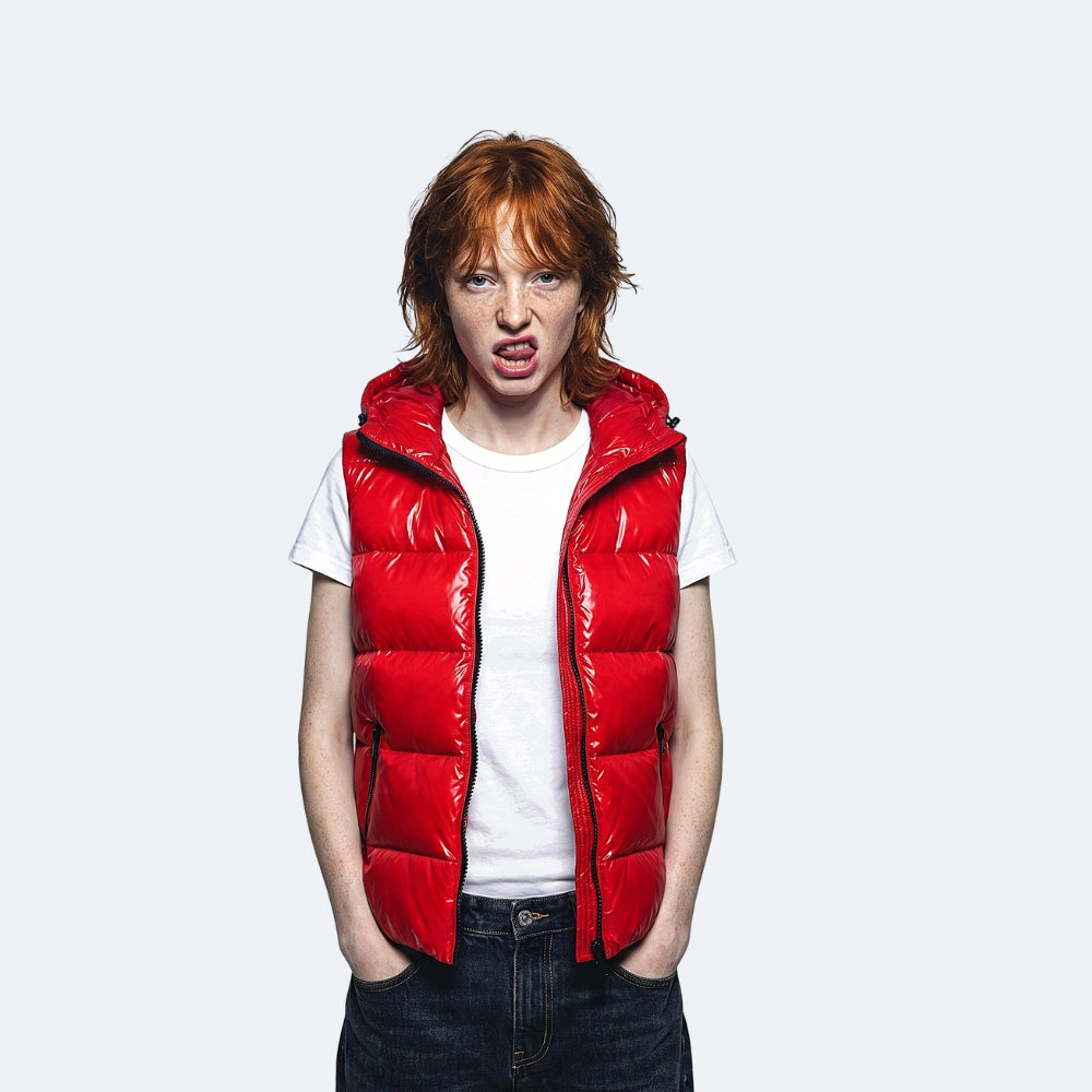 Red. A model with red hair wearing a shiny red puffer vest over a white t-shirt and dark jeans.