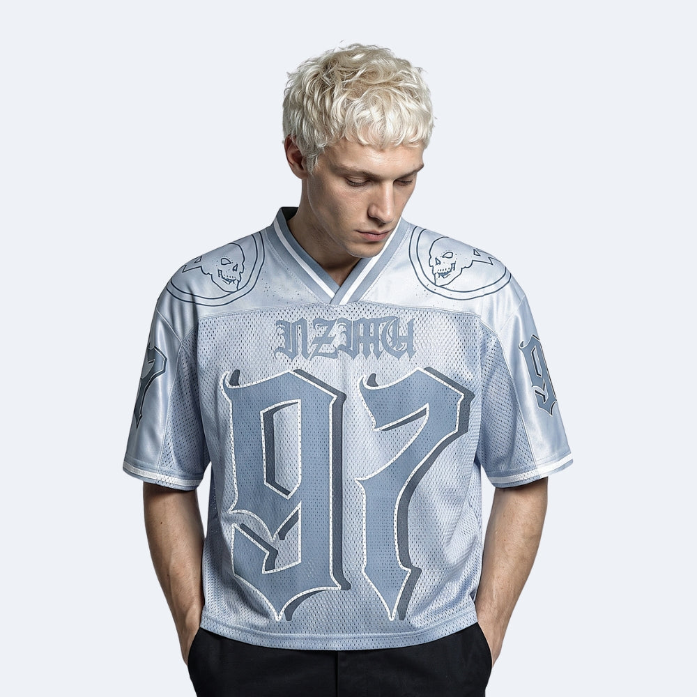 Blue. A man with platinum blonde hair wearing a light blue and gray gothic-style football jersey with the number 97 and the word MARCH on the chest.