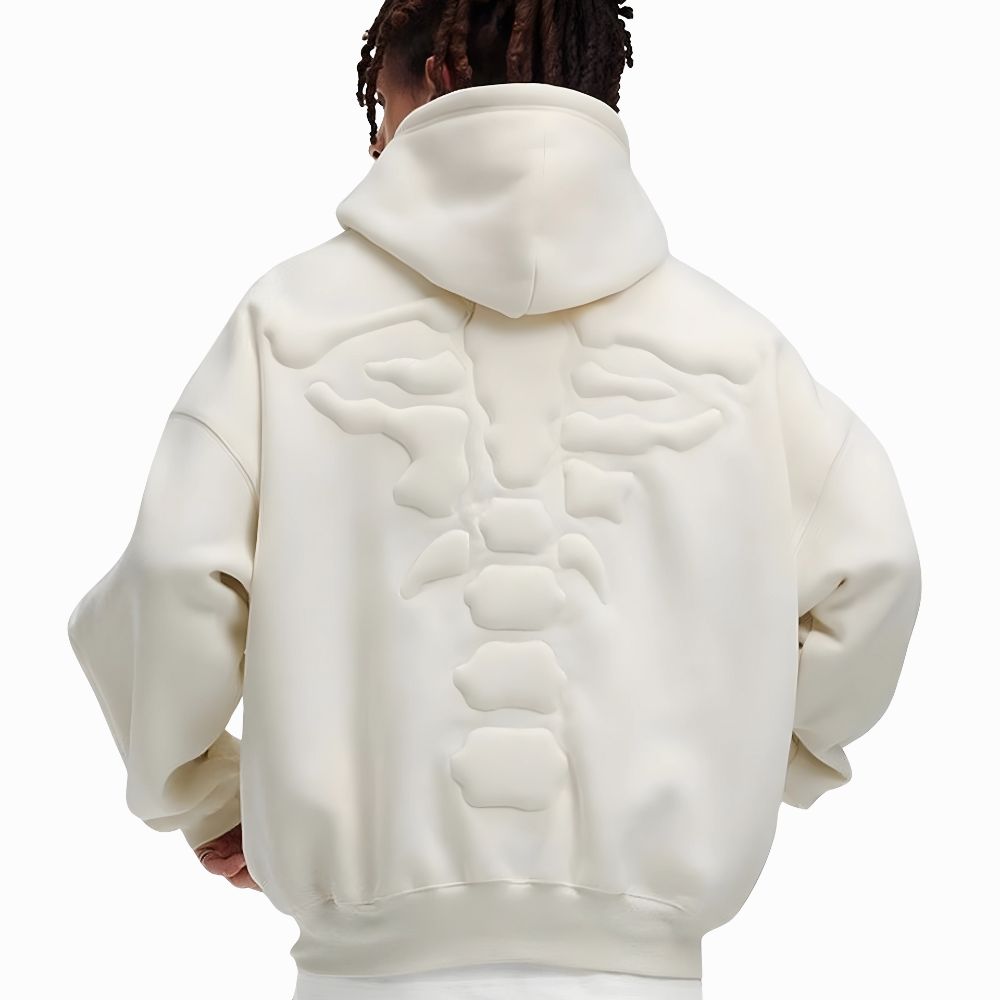 Person wearing a cream hoodie with a unique design on the back against a white background