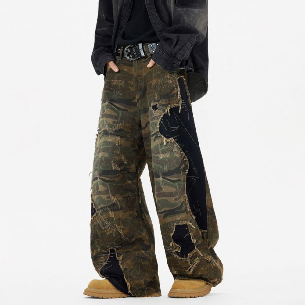 Person wearing camouflage pants with a black jacket on a white background