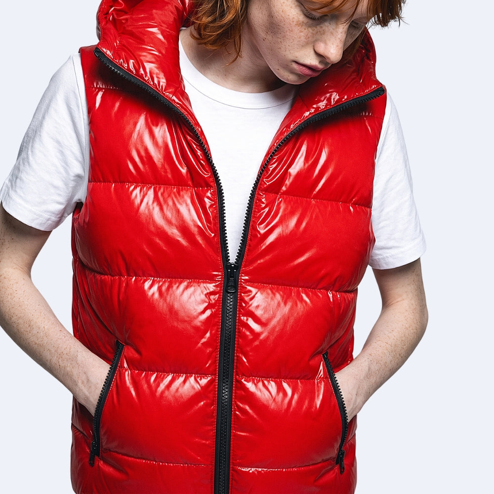 A person wearing a shiny red puffer vest over a white T-shirt, photographed against a light gray studio background.