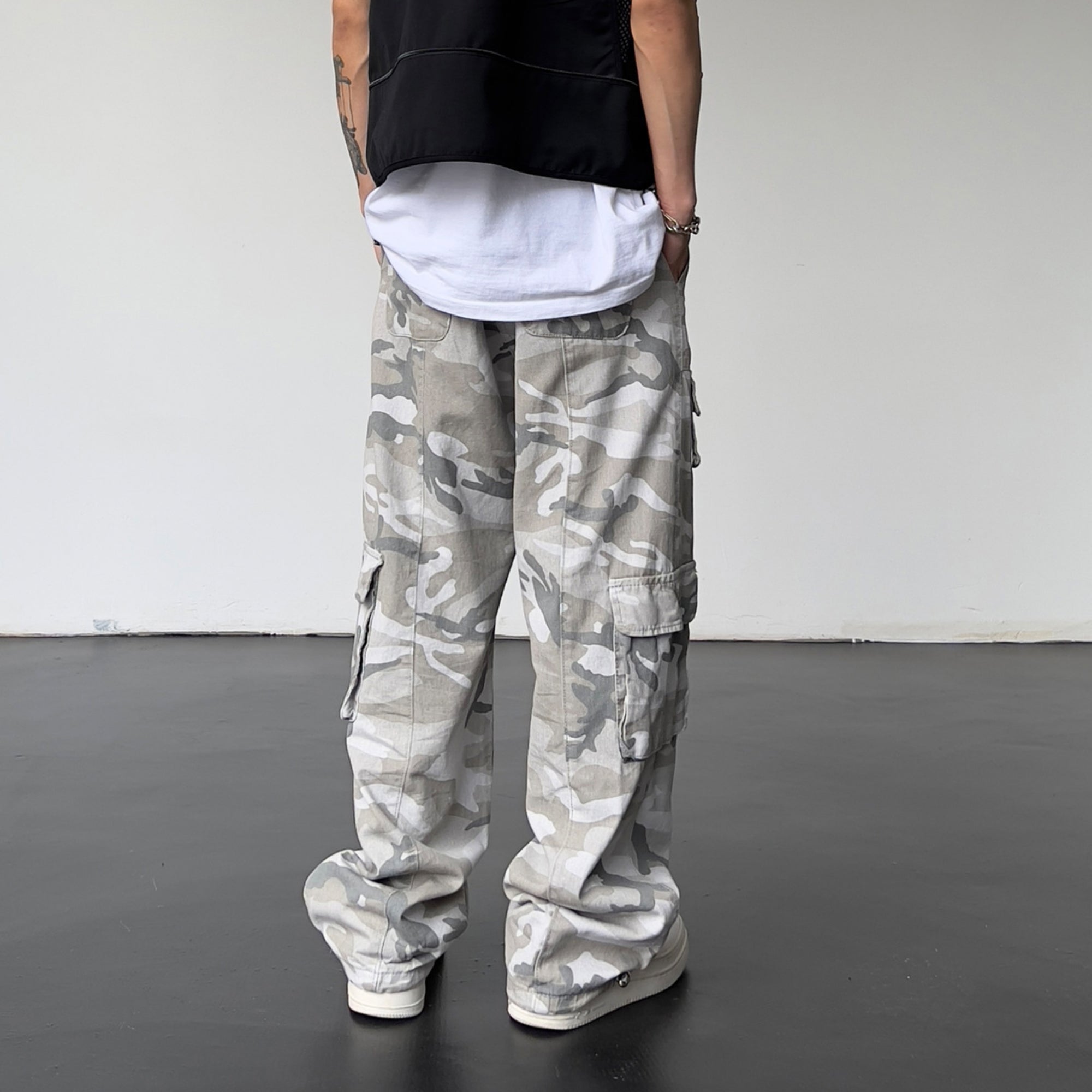 Person wearing camouflage cargo pants with a plain background