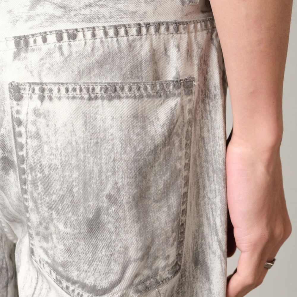 Close-up of a person wearing acid-wash jeans with a neutral background