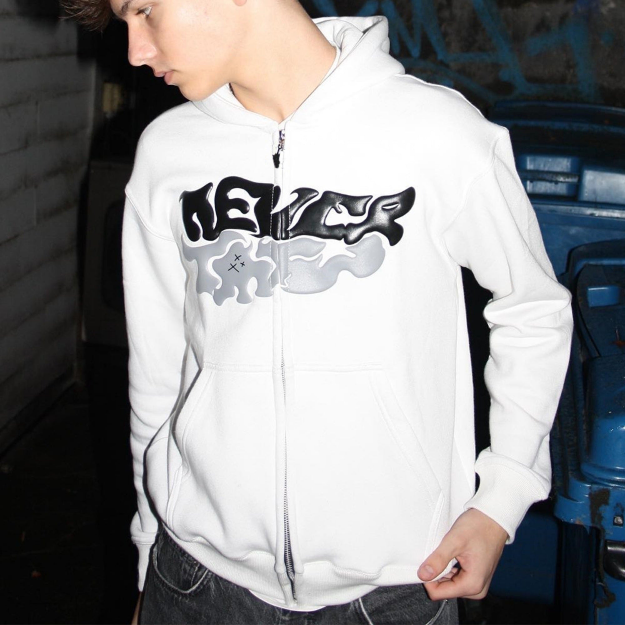 Person wearing a white hoodie with a logo in an indoor setting